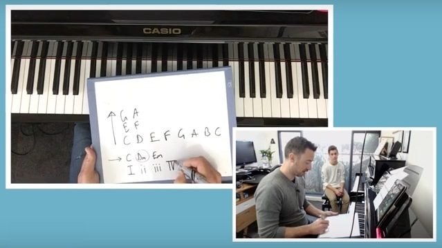 Tim at the piano with a student, writing chord numbers on a whiteboard